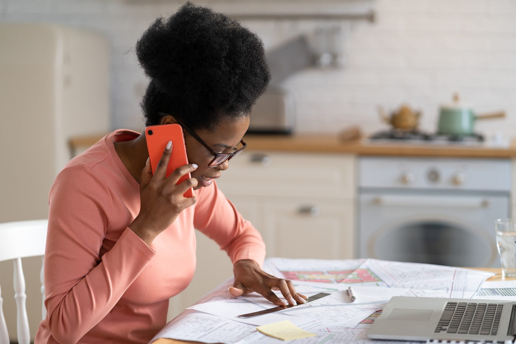 A woman working at a kitchen table while on the phone